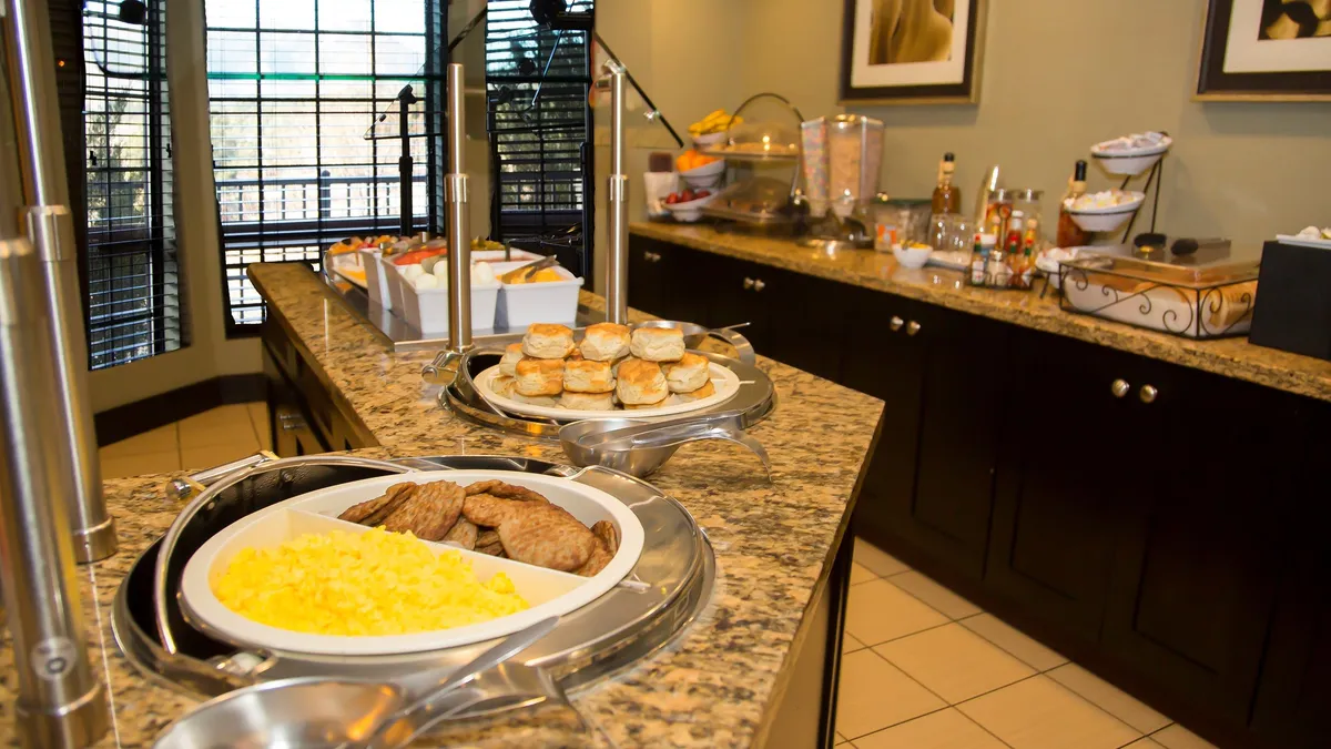 This image showcases the inviting breakfast buffet inside the condo. A granite countertop presents a tempting array of hot and cold breakfast options, with neatly arranged food items and serving utensils. The area radiates a sense of comfort—perfect for guests fueling up for a day of adventure or winding down with a relaxed meal. The social, welcoming atmosphere encourages guests to gather and connect over food.